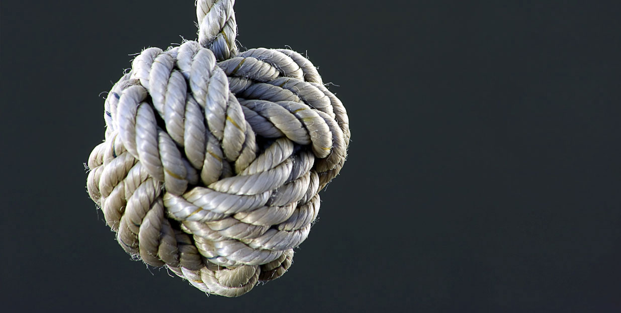 A rope is securely tied in a knot outdoors.