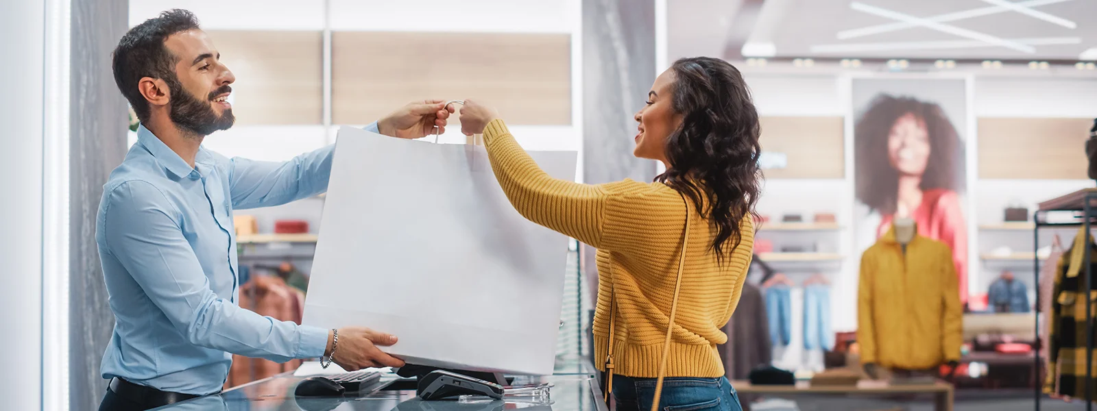 A photo of a retail worker handing a bag to a customer