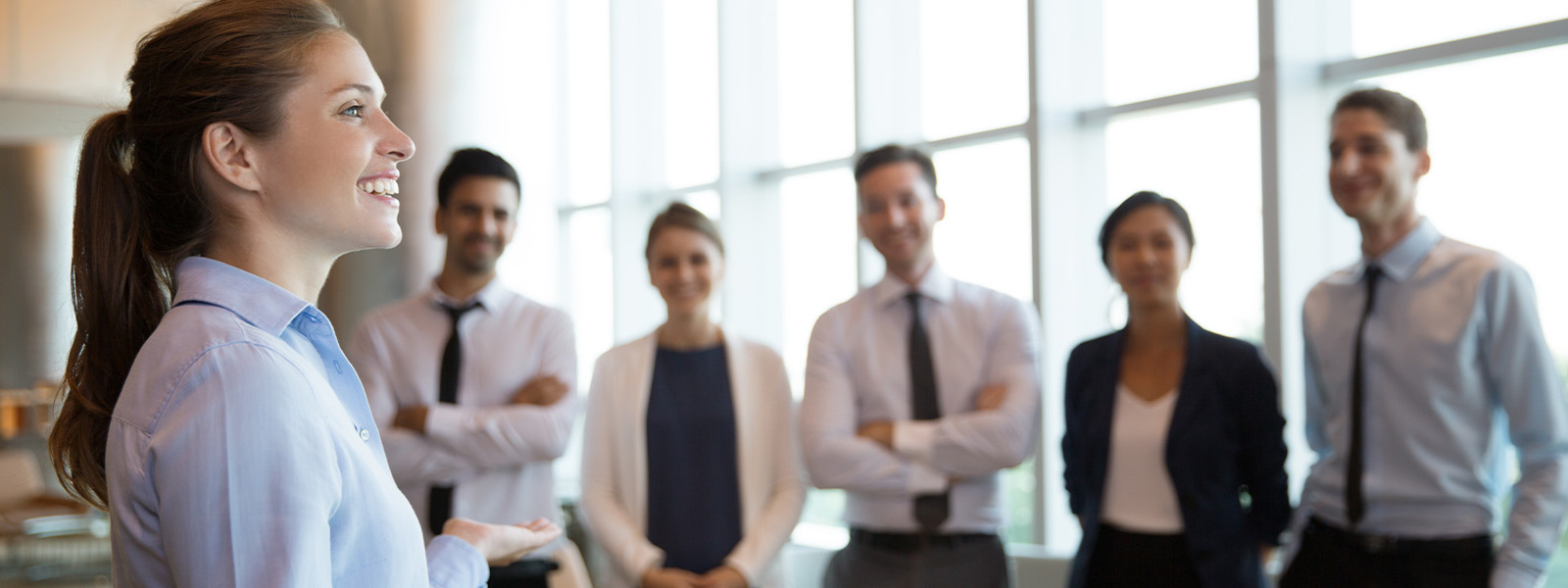 A group of people wearing shirts are standing together indoors, smiling and enjoying their job.