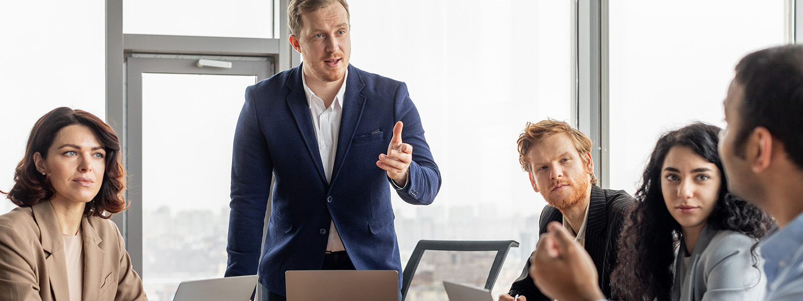 Business professional leading a discussion with a focused group of colleagues during a meeting.