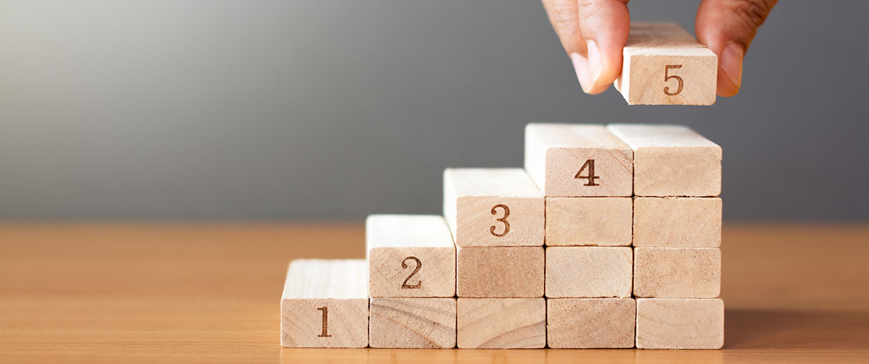 A person is arranging wooden blocks in a box from 5 to 1.