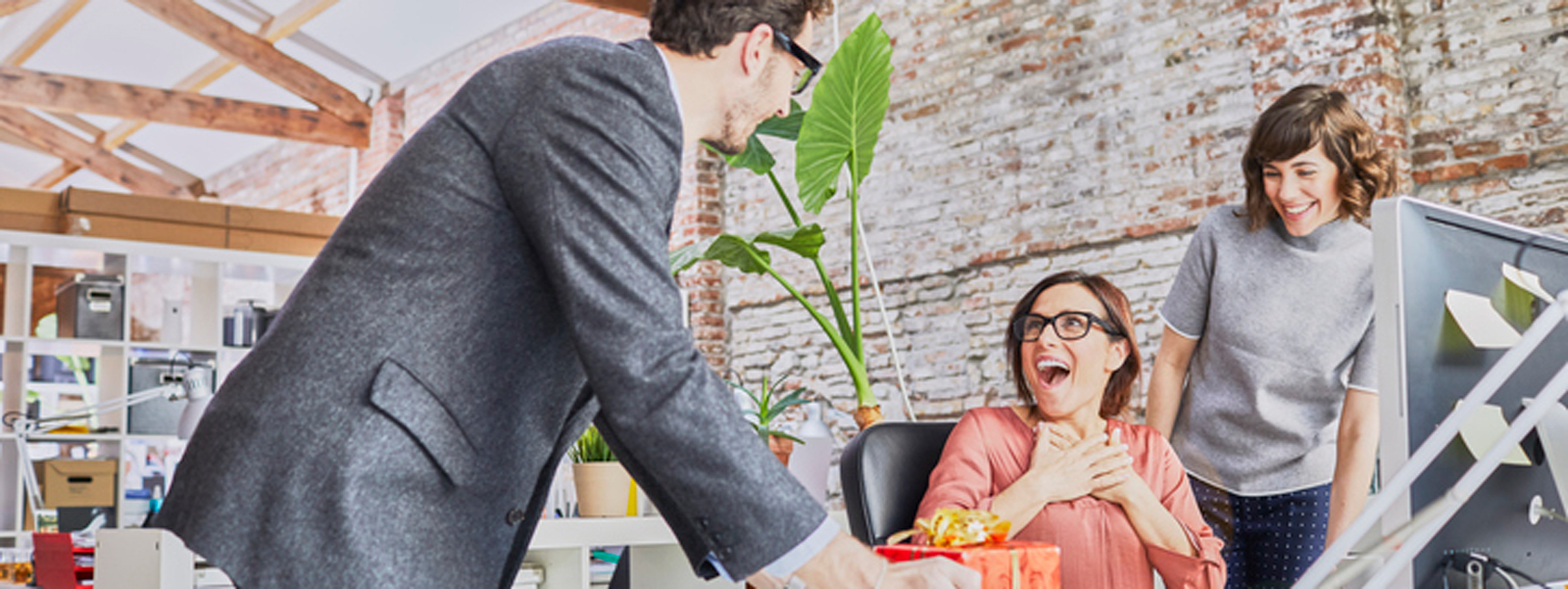 a woman is surprised by a gift from her coworkers