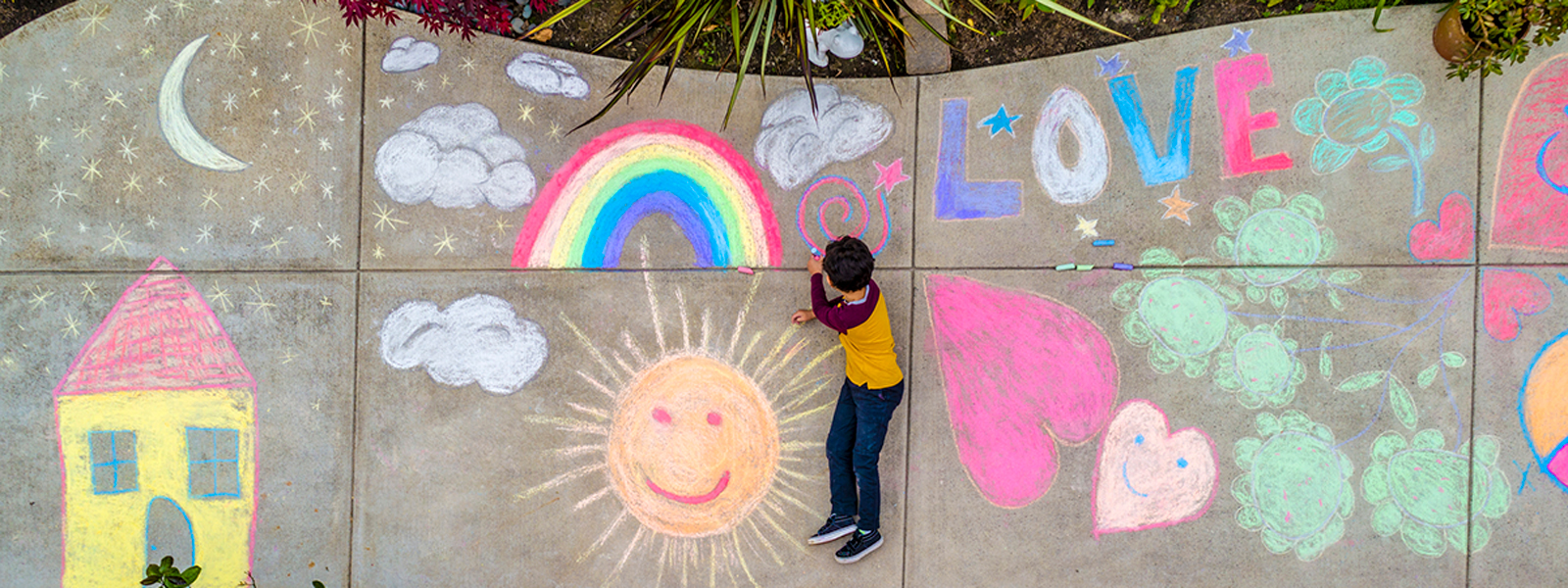 a child draws on the sidewalk