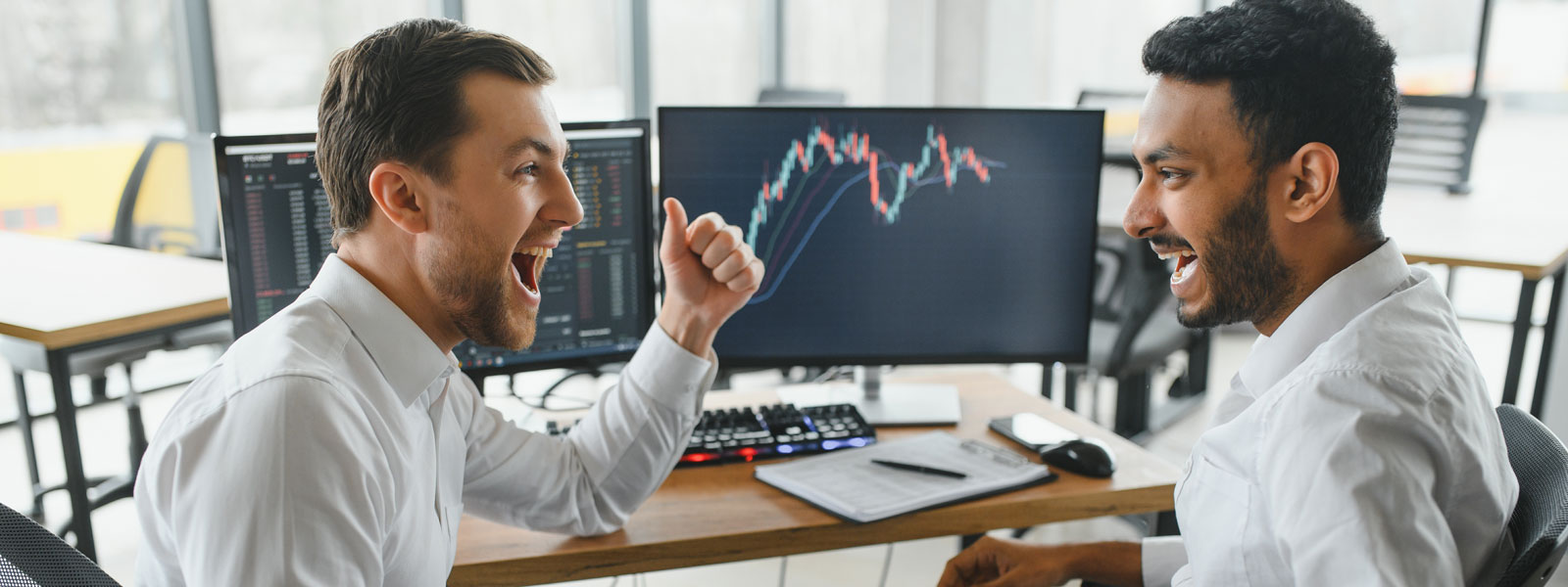 A photo of two happy businessmen reviewing a numbers and graphs on a computer screen